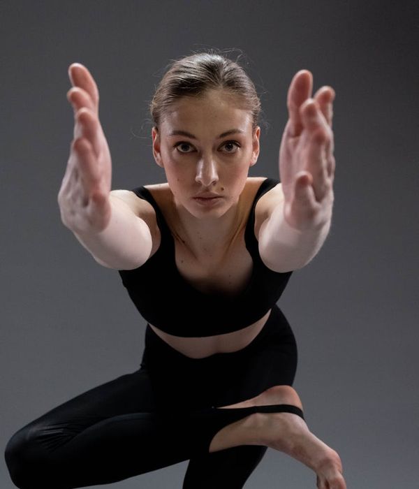 Woman in a calm yoga pose in a dark, serene studio.